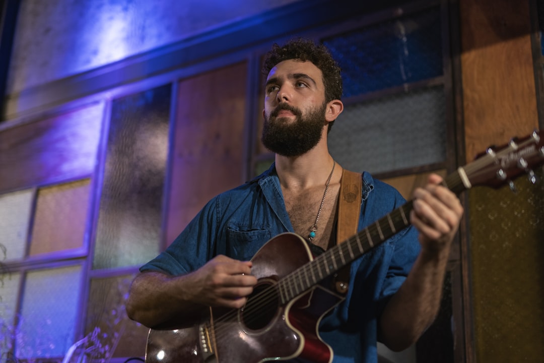 man in blue dress shirt playing guitar