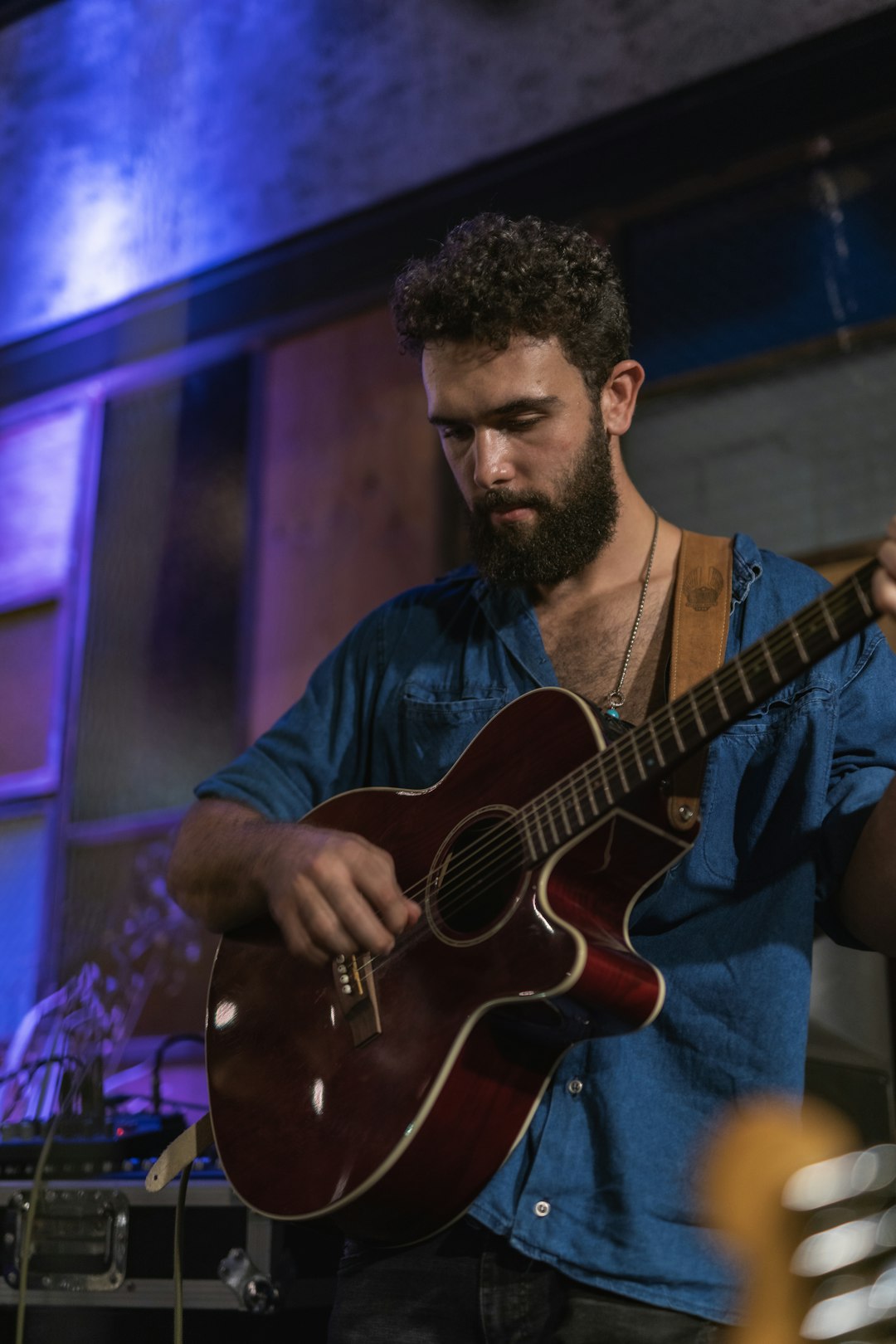 man in blue crew neck t-shirt playing brown acoustic guitar