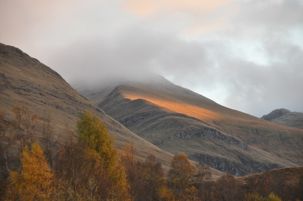 brown and green mountains under white clouds during daytime