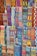 A vibrant array of intricately woven textile patterns featuring geometric designs. The textiles display a rich variety of colors and intricate details, arranged in rows and showcasing a range of traditional and cultural motifs.