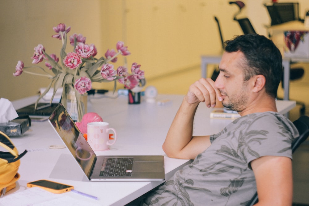 Mann in Grau Rundhals-T-Shirt mit MacBook Pro