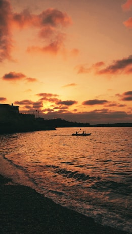 Two kayaks floating gently on calm water near a scenic cove at sunset.