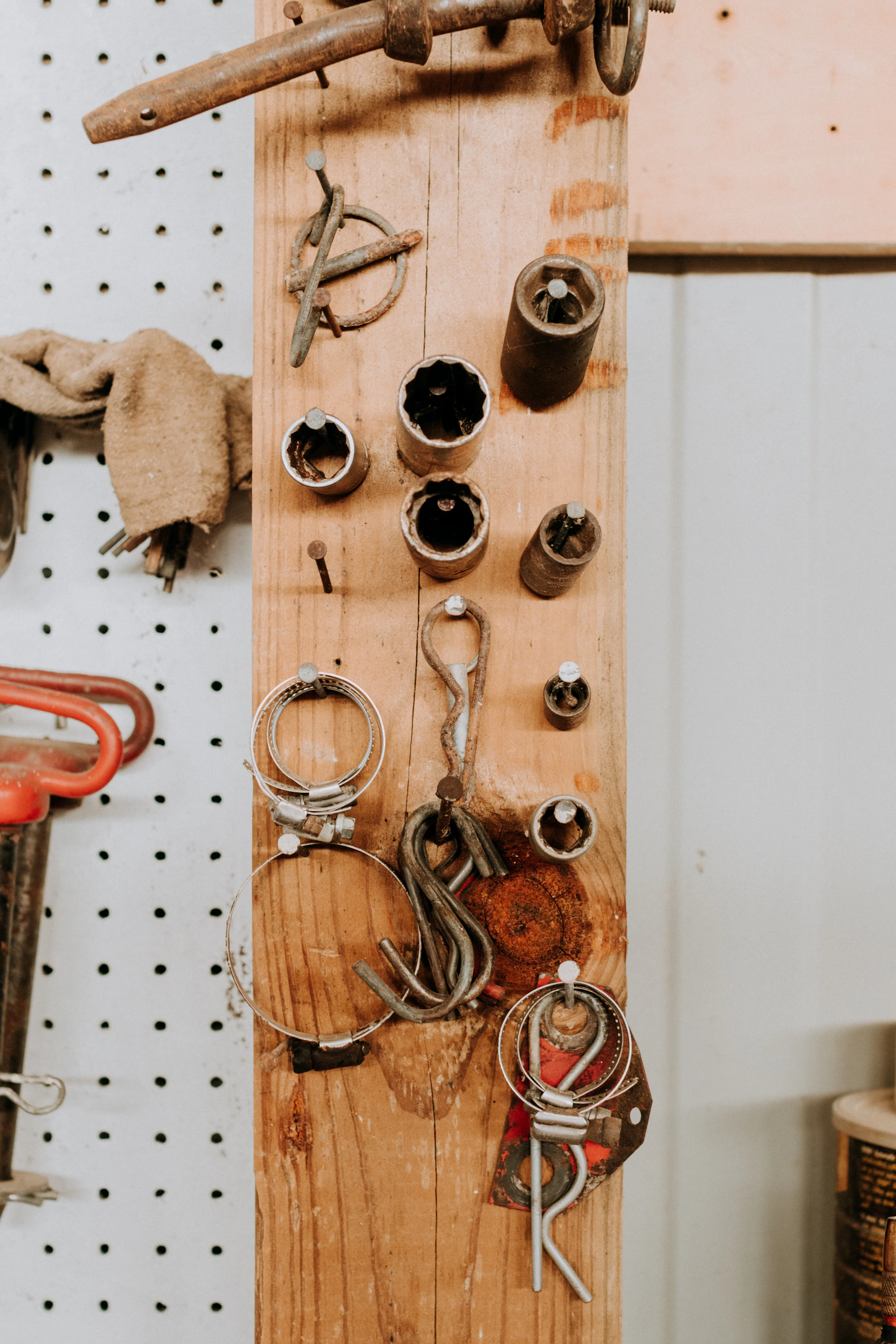 A plywood pegboard wall hung with clamps, a spring, and hand tools