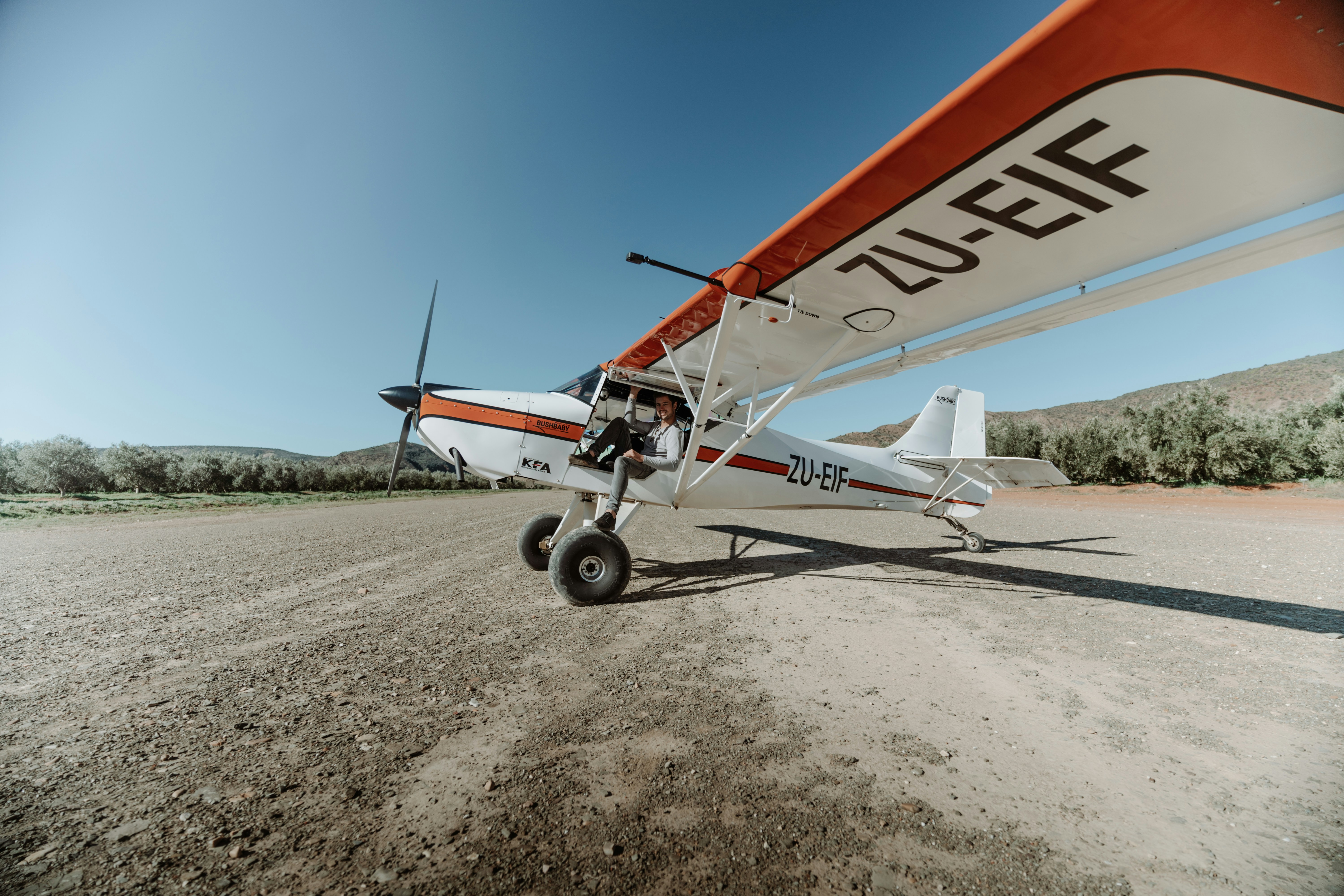 white and red airplane on brown field during daytime