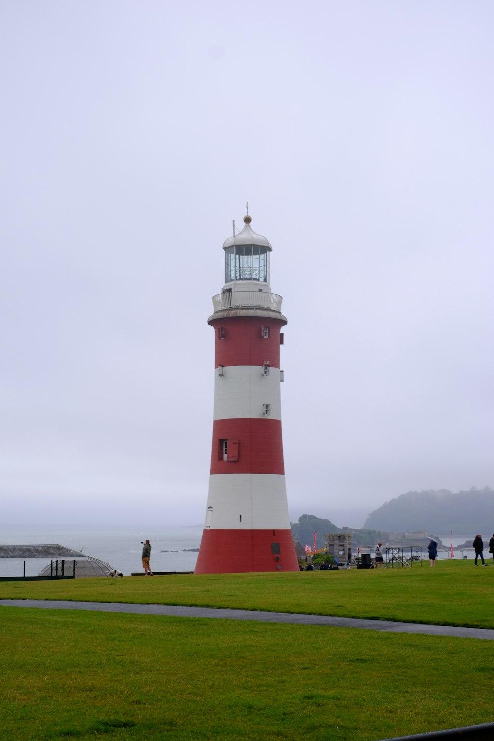 red and white lighthouse on green grass field under white sky during daytime