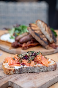 Close-up of a beautifully smoked salmon fillet garnished with fresh herbs on a rustic wooden board.