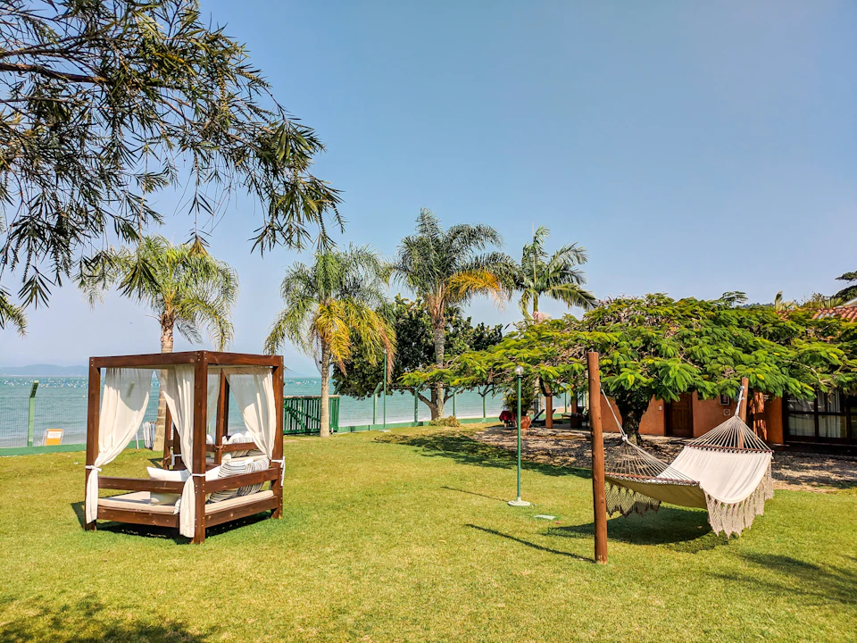 Serene tropical garden scene features white canopy tent and lounge chairs under palm tree shade
