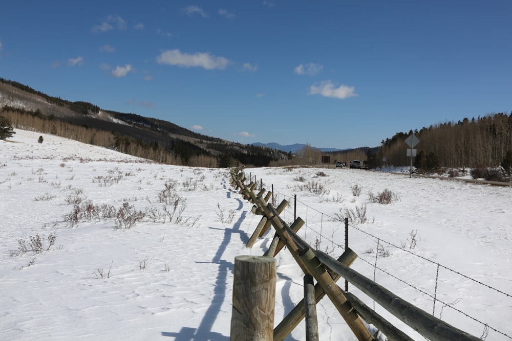 brown wooden fence on snow covered ground during daytime