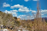 Front view of a rustic Andean bungalow surrounded by green hills under a clear sky.