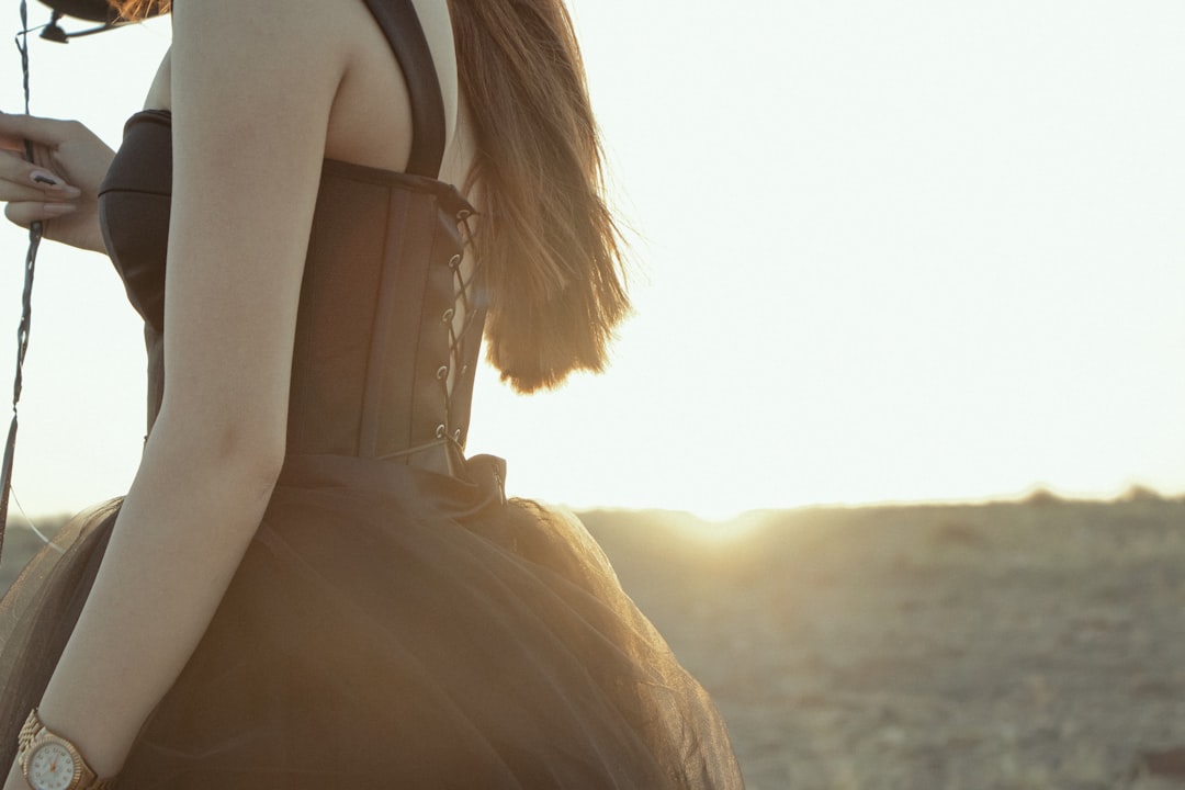 woman in white shirt standing on beach during sunset