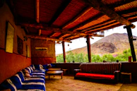 A cozy outdoor seating area with wooden furniture overlooking a green valley.