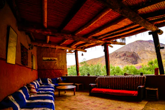 A cozy outdoor seating area with wooden furniture overlooking a green valley.