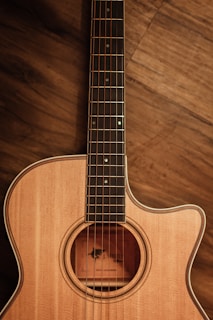 brown acoustic guitar on brown wooden floor