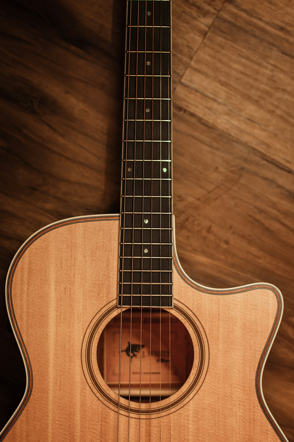 chitarra acustica marrone su pavimento di legno marrone