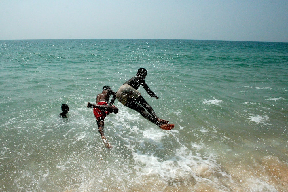 2 men in black shorts playing on sea during daytime