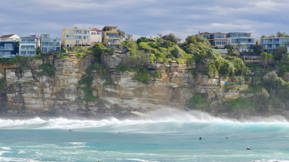 white and brown concrete building near sea waves crashing on shore during daytime