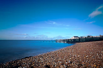 Cozy seaside guesthouse with sandy beach visible in the background under a clear sky.