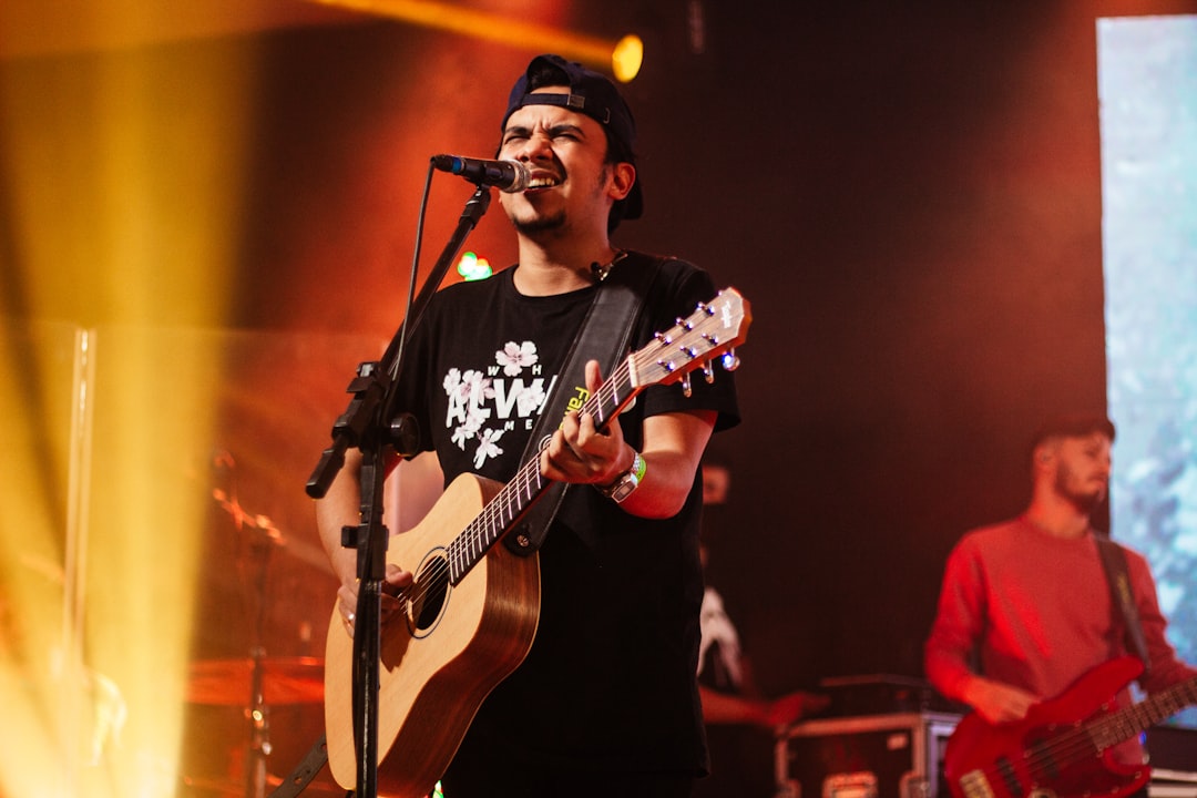 man in black and white crew neck t-shirt playing guitar