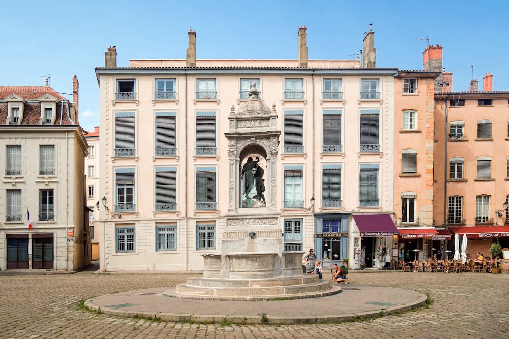 personnes marchant dans la rue près d’un bâtiment en béton blanc pendant la journée