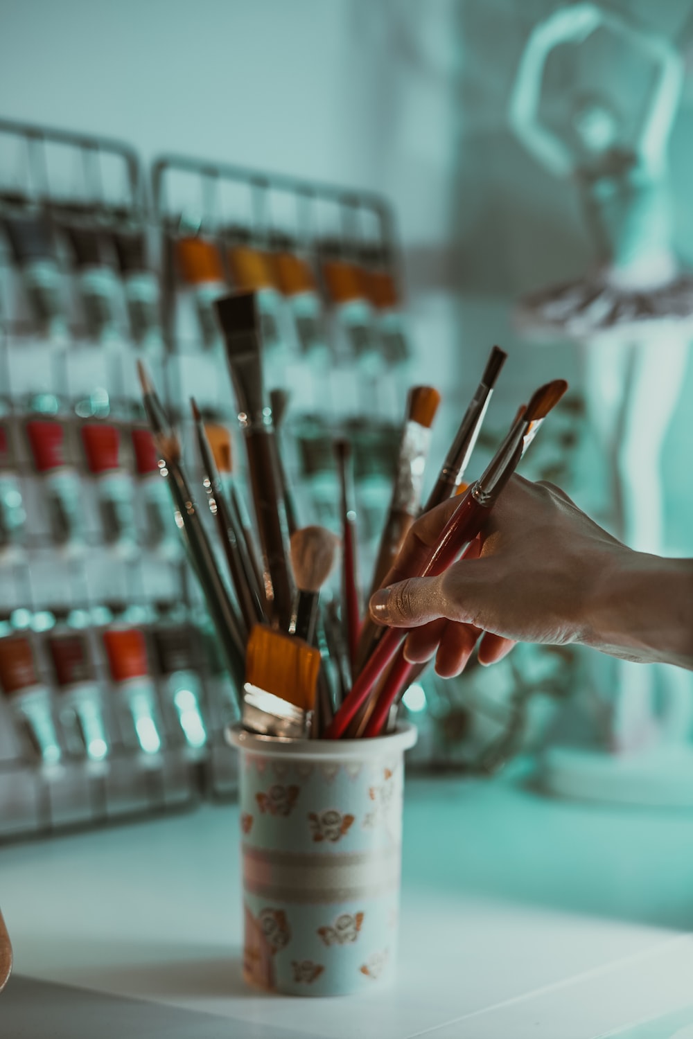 person holding paint brush in white paint bucket