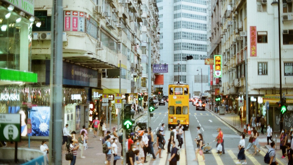 낮에 노란색 버스 근처 거리를 걷는 사람들