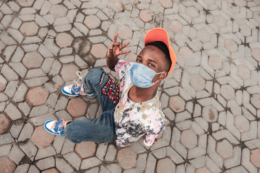 girl in white floral shirt and blue denim jeans standing on brown brick floor