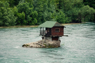 brown wooden house on brown rock formation beside body of water during daytime Serbia