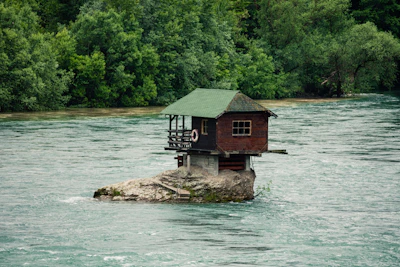 brown wooden house on brown rock formation beside body of water during daytime Serbia