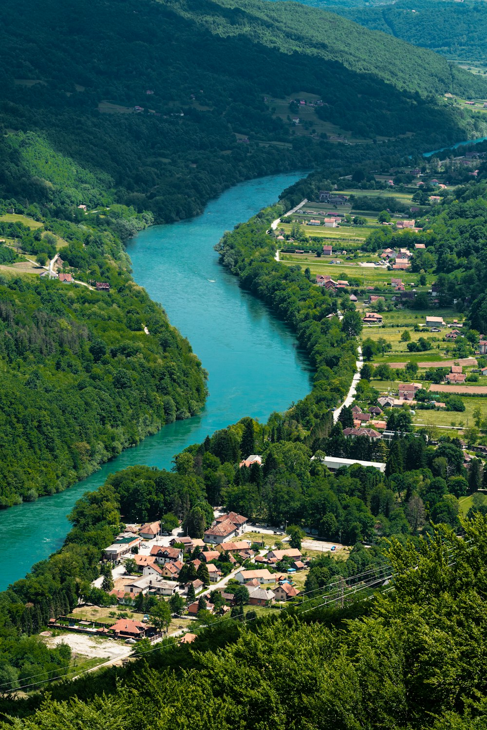 aerial view of green lake surrounded by green trees during daytime