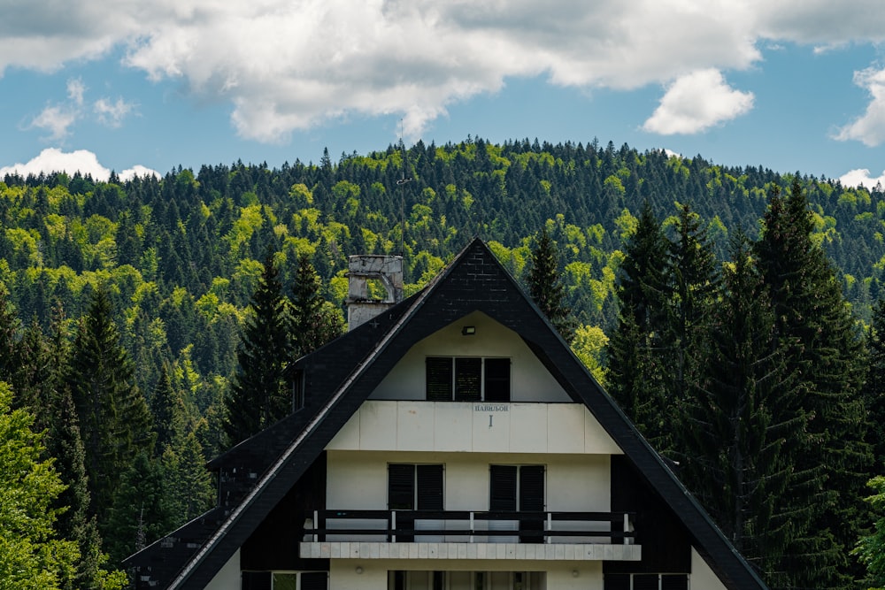 white and brown wooden house surrounded by green trees under white clouds and blue sky during