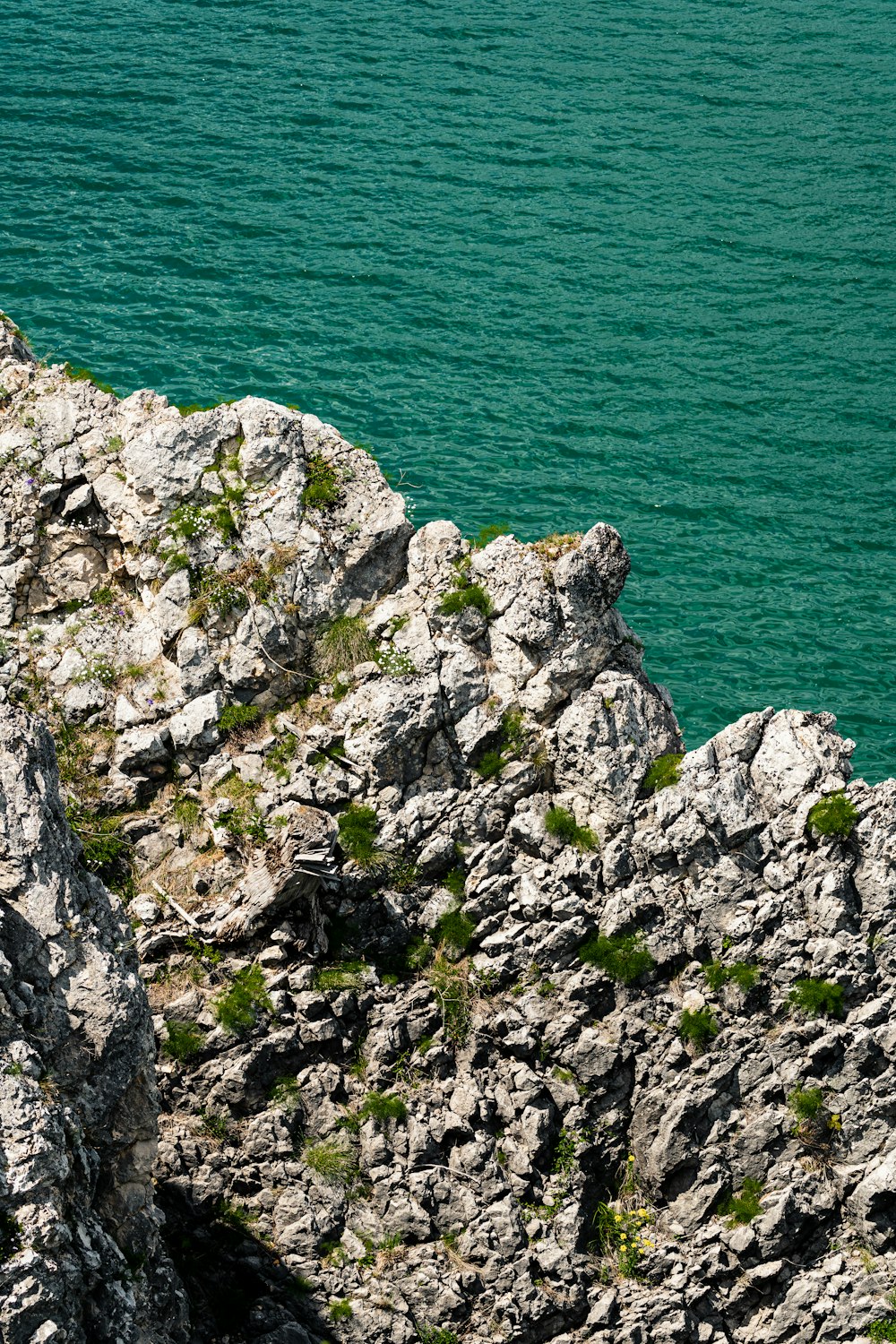 gray rocky mountain beside body of water during daytime