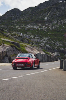 A bright red convertible cruising along a winding mountain road.