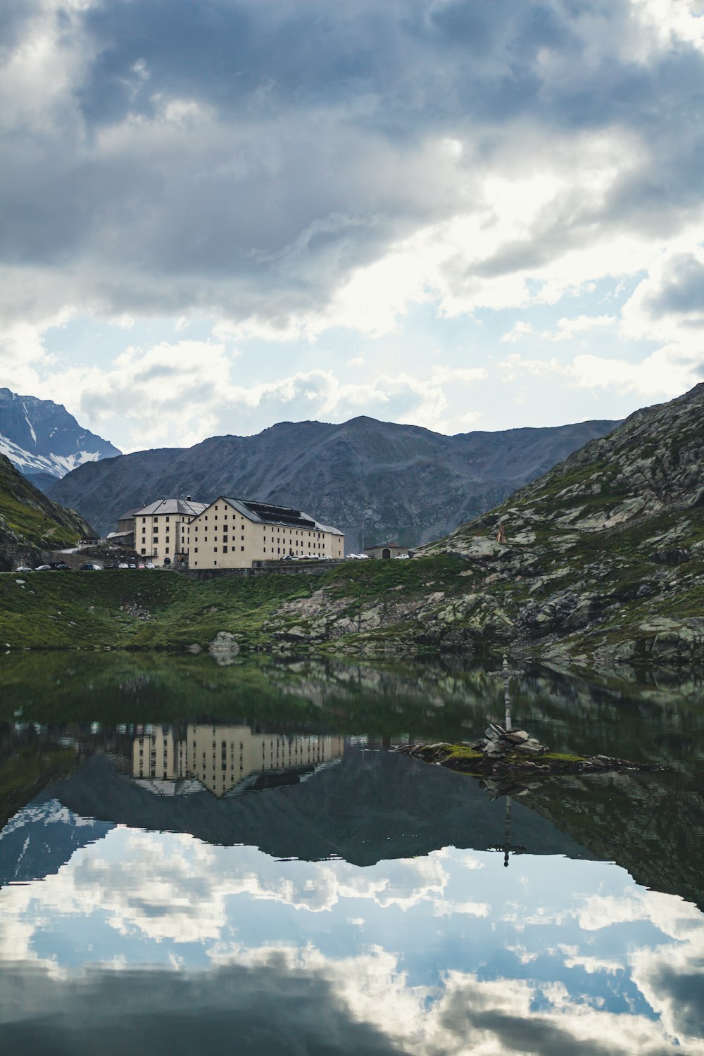 white and brown concrete building near green mountains under white clouds and blue sky during daytime