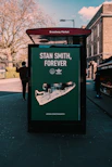 man in black jacket standing beside green and white signage