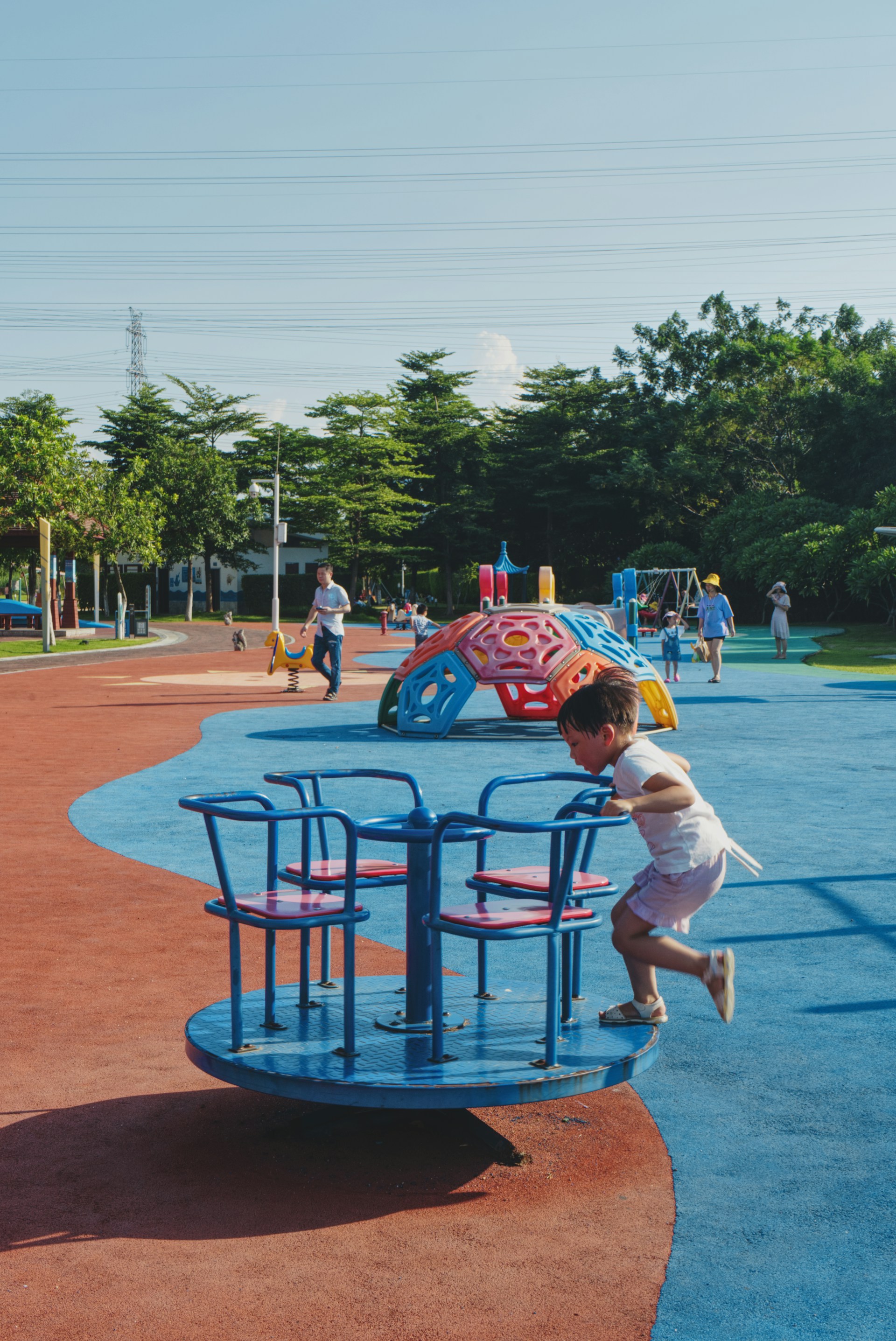 girl in white t-shirt and blue shorts sitting on blue metal chair during daytime