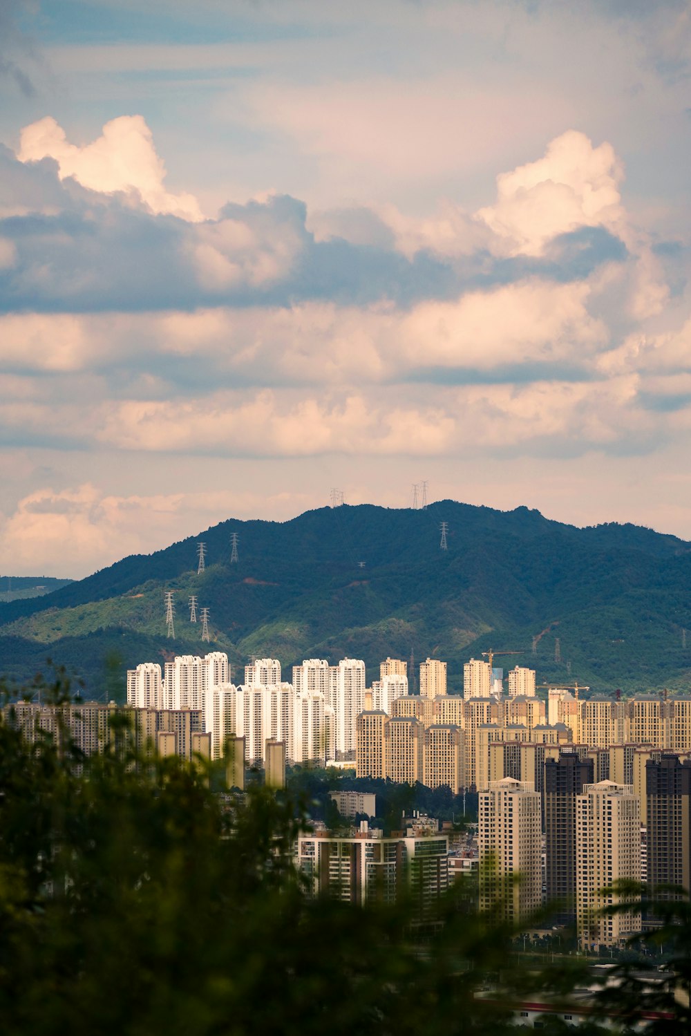 white concrete building near green mountain under white clouds during daytime