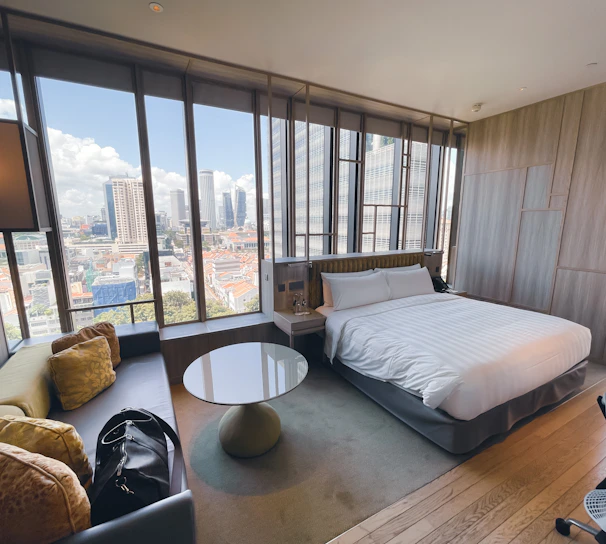 Luxurious deluxe suite with plush furnishings and a balcony overlooking the city skyline.