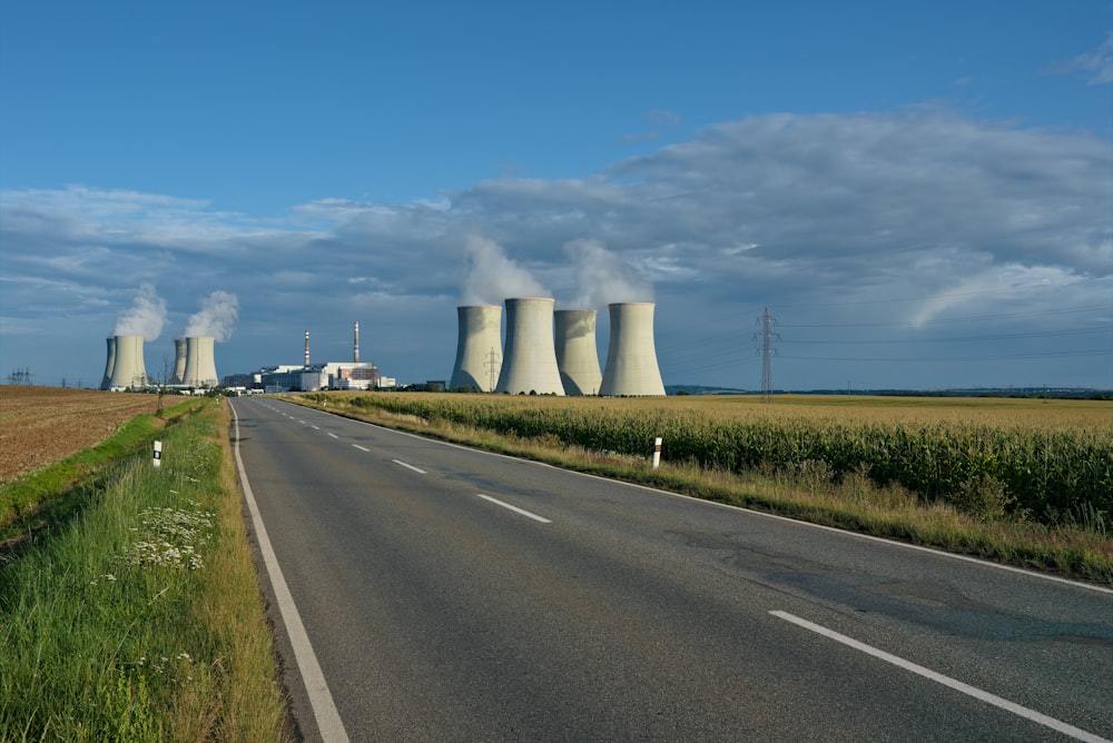 Graue Asphaltstraße zwischen grünem Rasenfeld unter blauem Himmel tagsüber