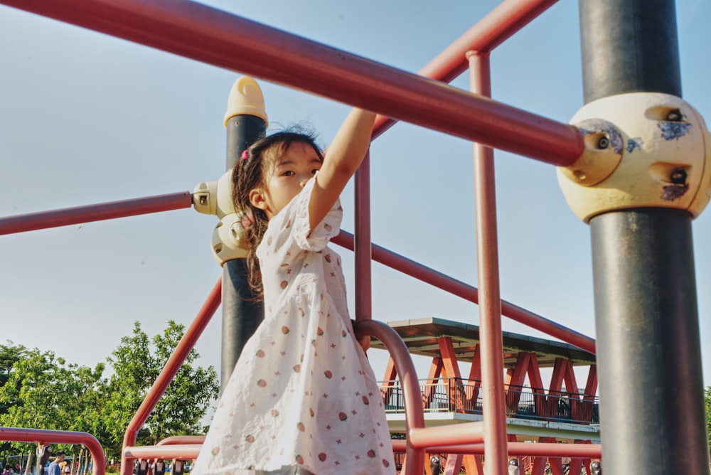 girl in pink dress on red and white metal bar