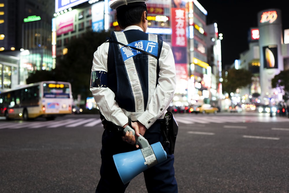 homem na jaqueta azul e branca que segura o copo de plástico azul