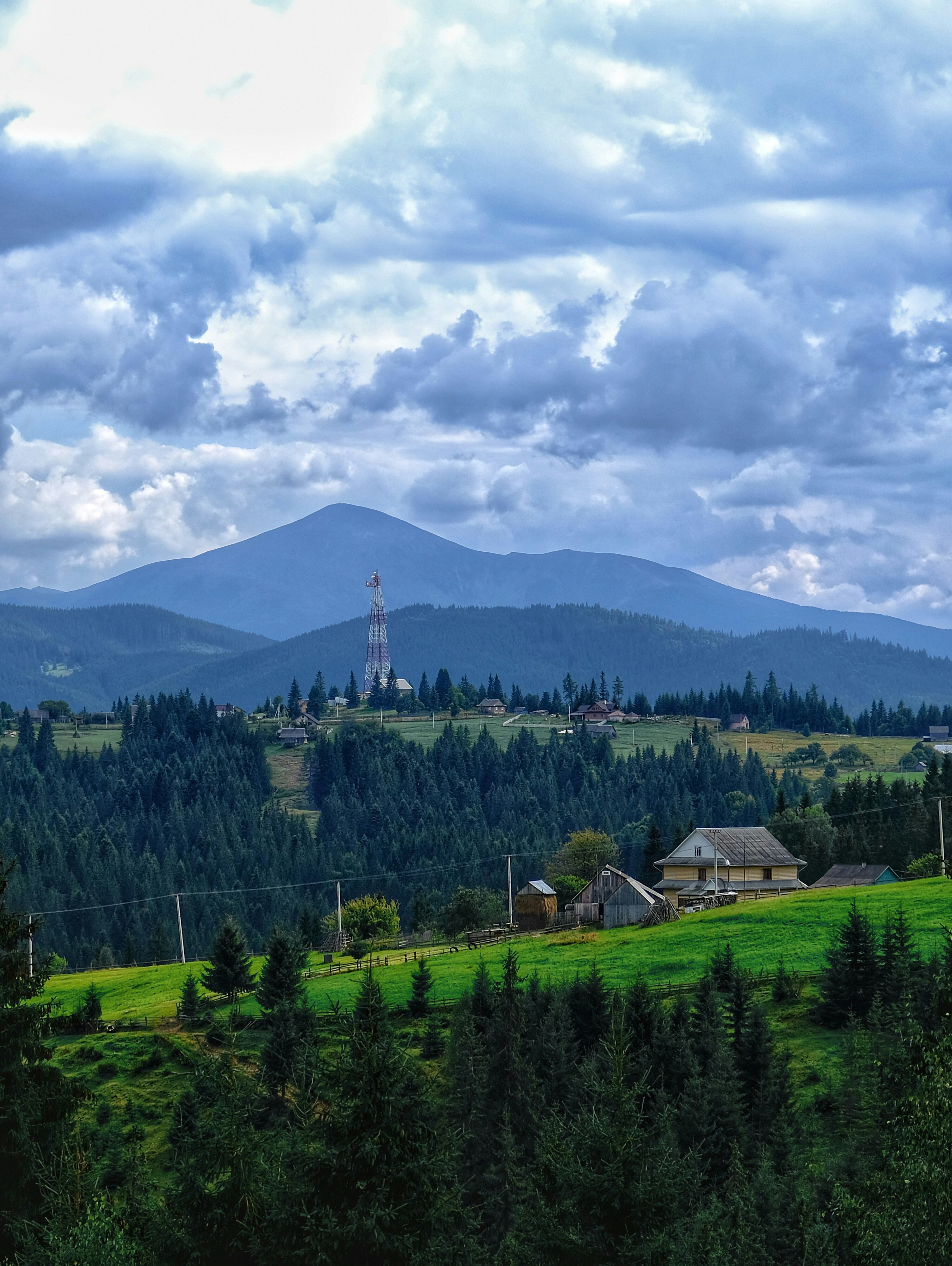 green trees and mountains under white clouds and blue sky during daytime