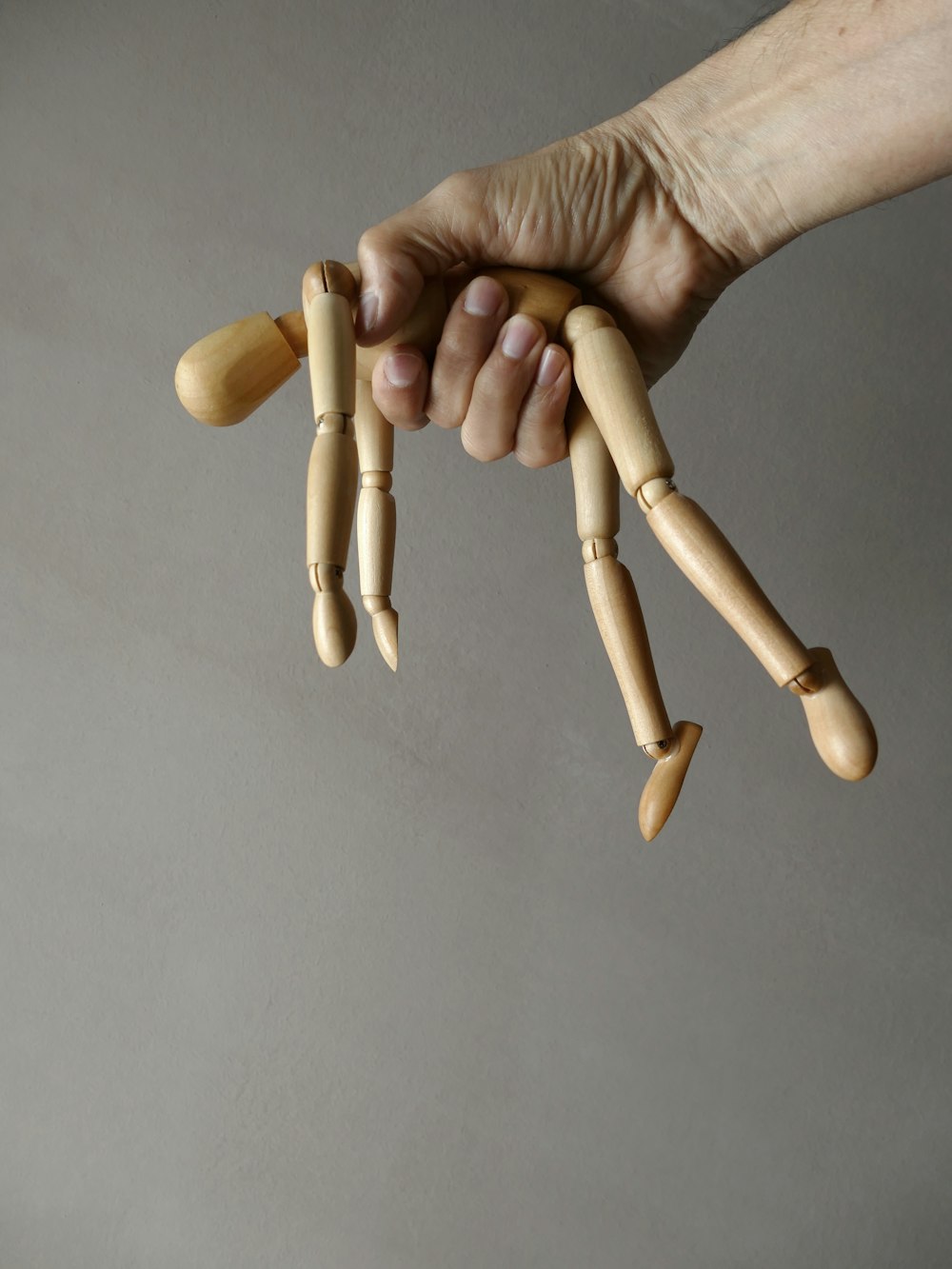 person holding brown wooden mannequin