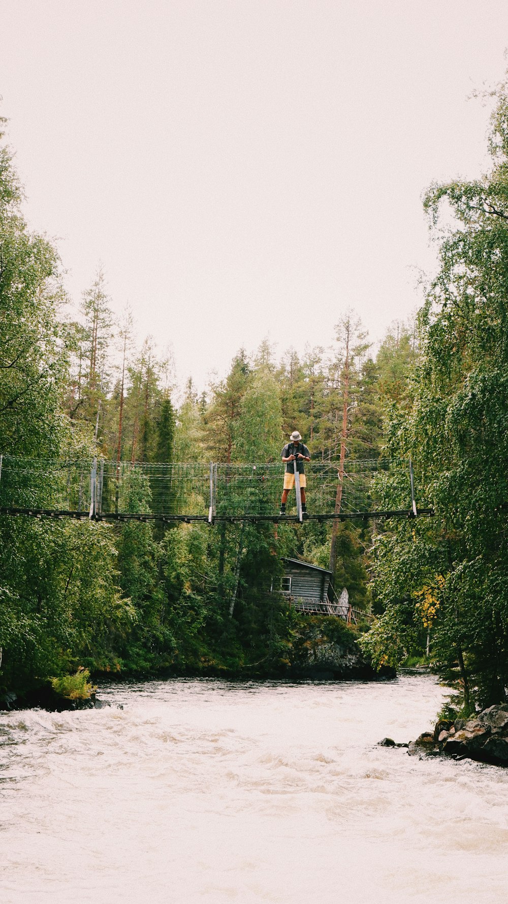 man in black t-shirt and black shorts standing on bridge over river during daytime