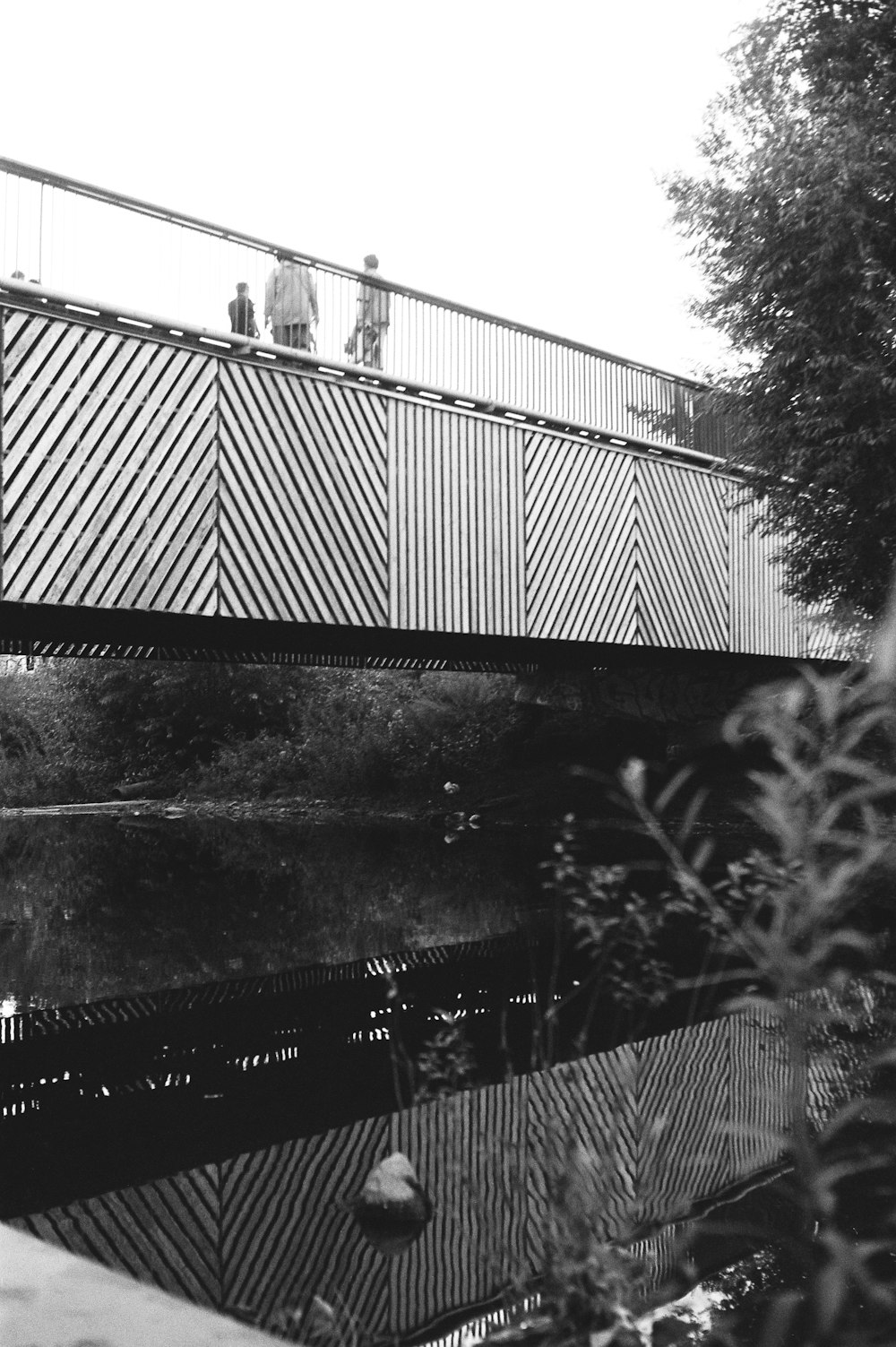 Foto in scala di grigi di un uomo in piedi sul ponte