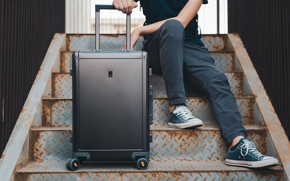 a person sitting on a set of stairs with a suitcase