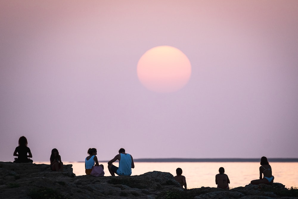 people sitting on rock formation near sea during daytime