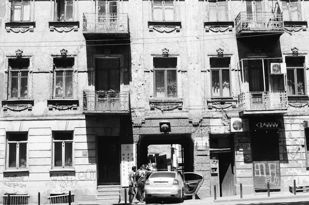 grayscale photo of cars parked in front of building