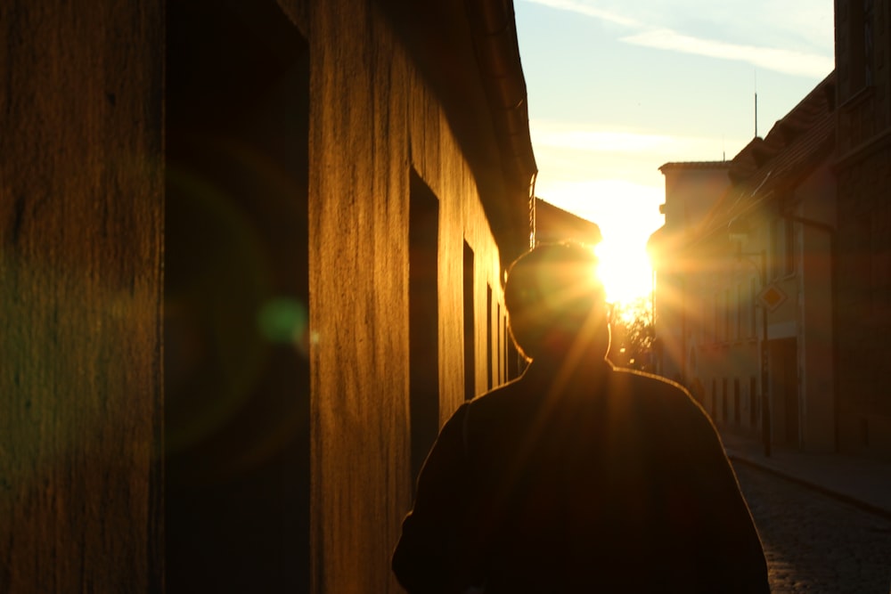 silhouette of person standing near brown wooden fence during daytime