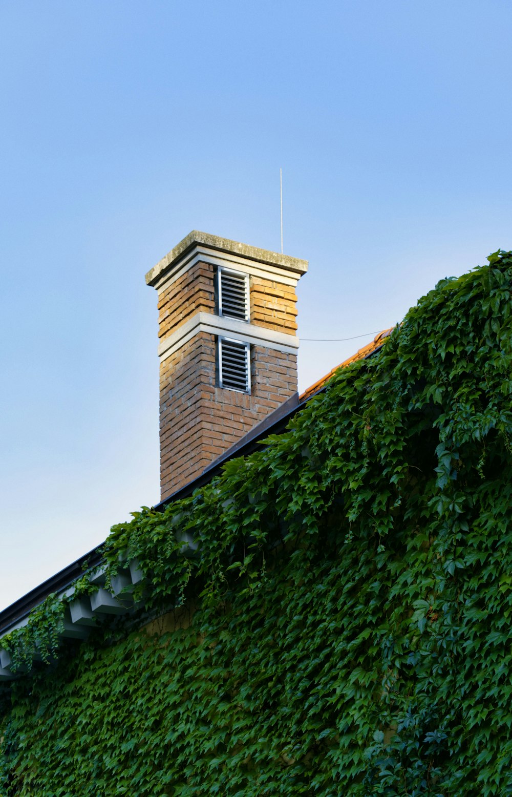 brown brick house near green trees under blue sky during daytime