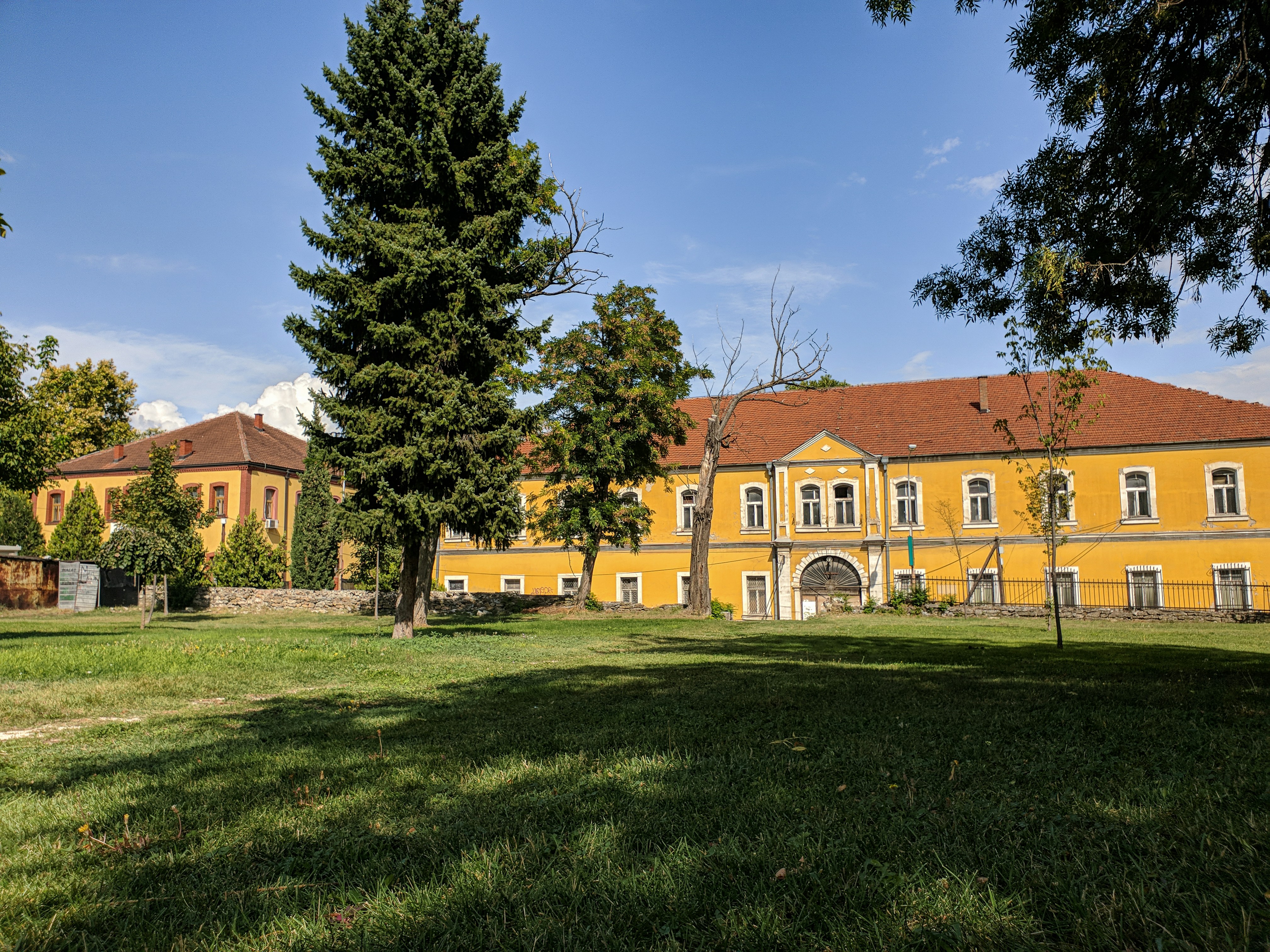 brown and white concrete house near green trees under blue sky during daytime